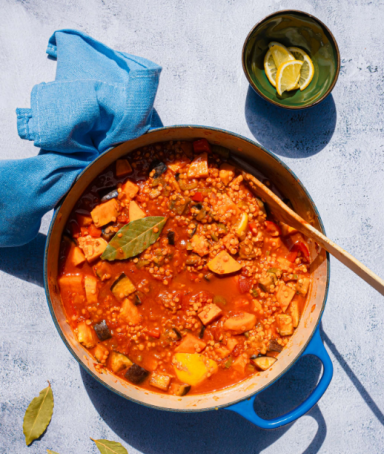 Een pan met stoofpot, garnished met laurierbladen en een kom met citroenpartjes ernaast.