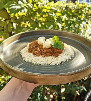 Bord met rijst, stoofpot en garnituren van munt en een paar bolletjes.