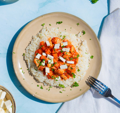 Gekruide rijst met tomatensaus en blokjes feta, mogelijk met verse kruiden.